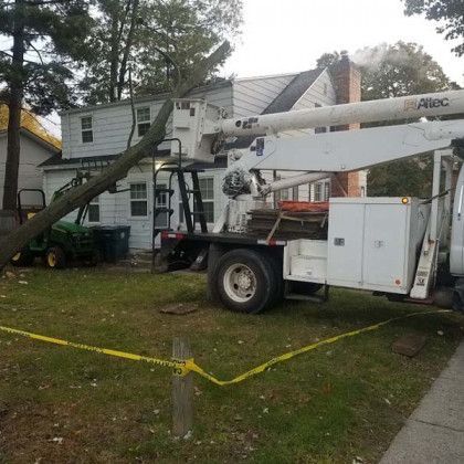 A white truck with a crane on the back is parked in front of a house.