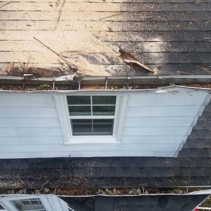 A house with a roof that is missing shingles and a window.