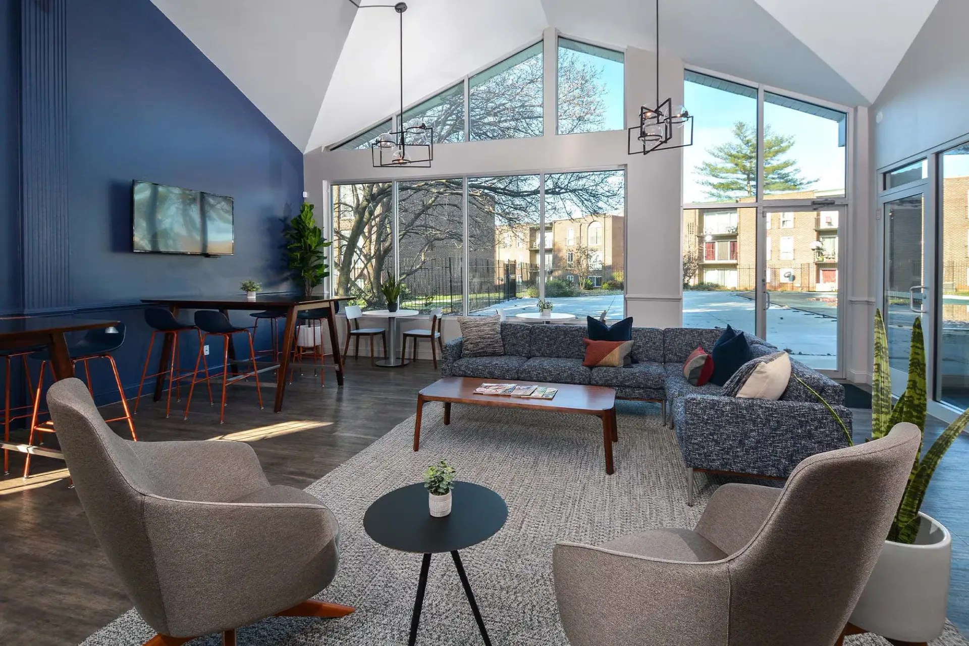 Bright modern resident lounge with large windows, contemporary seating, and a blue accent wall at Metro Pointe in Baltimore, MD.