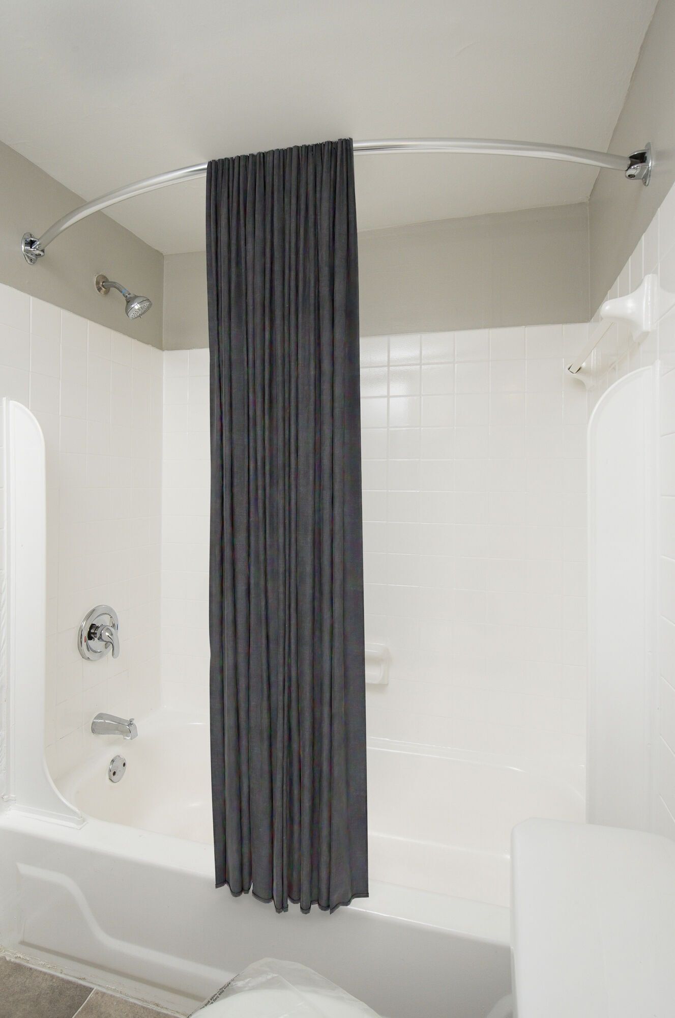 White-tiled bathroom with a bathtub and dark curved shower curtain at Metro Pointe in Baltimore, MD.