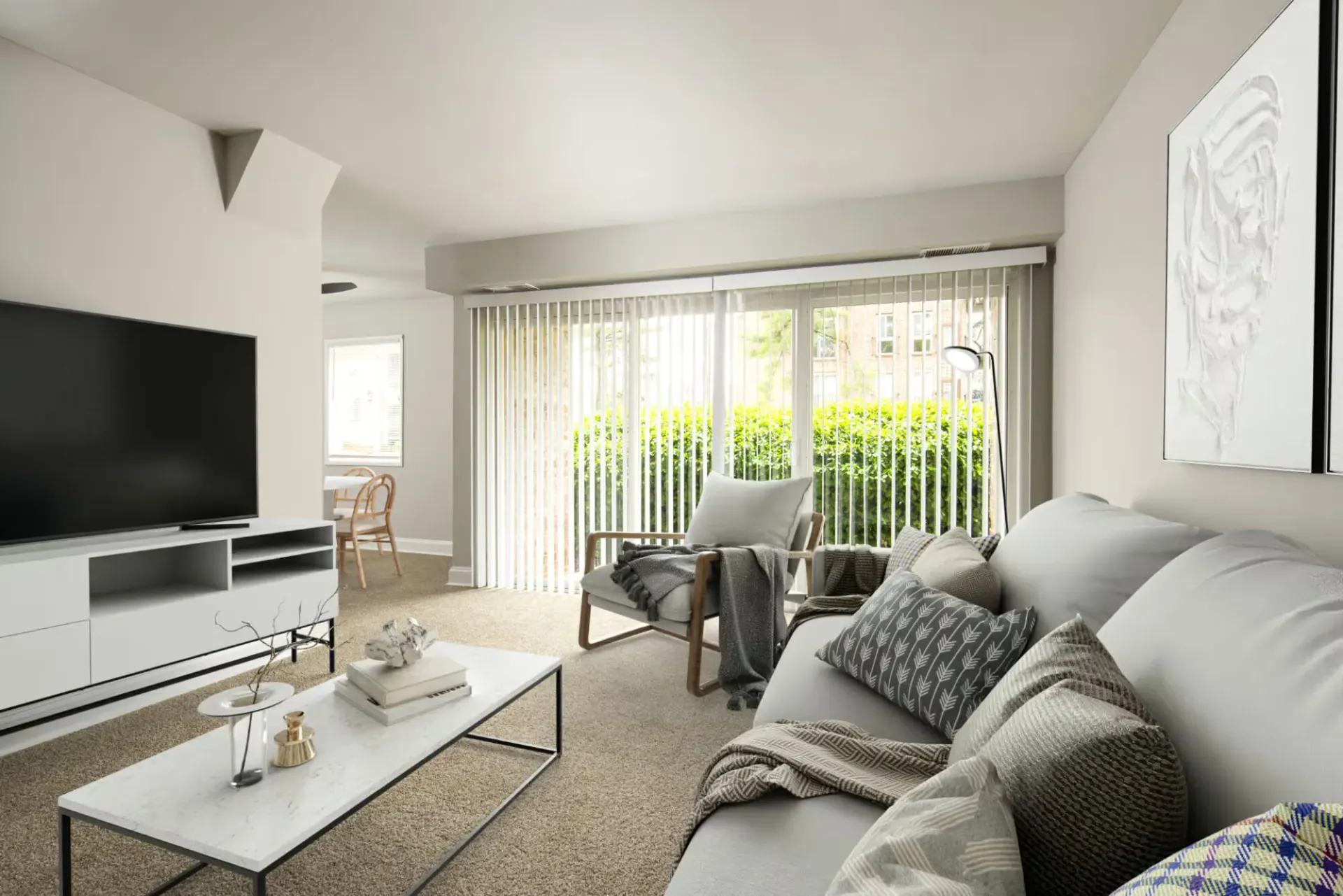 Bright apartment living room with sliding glass doors, vertical blinds, a sofa, and a coffee table at Metro Pointe in Baltimore, MD.