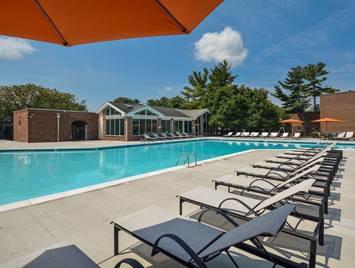 Outdoor community pool with lounge chairs and umbrellas at Metro Pointe in Baltimore, MD.