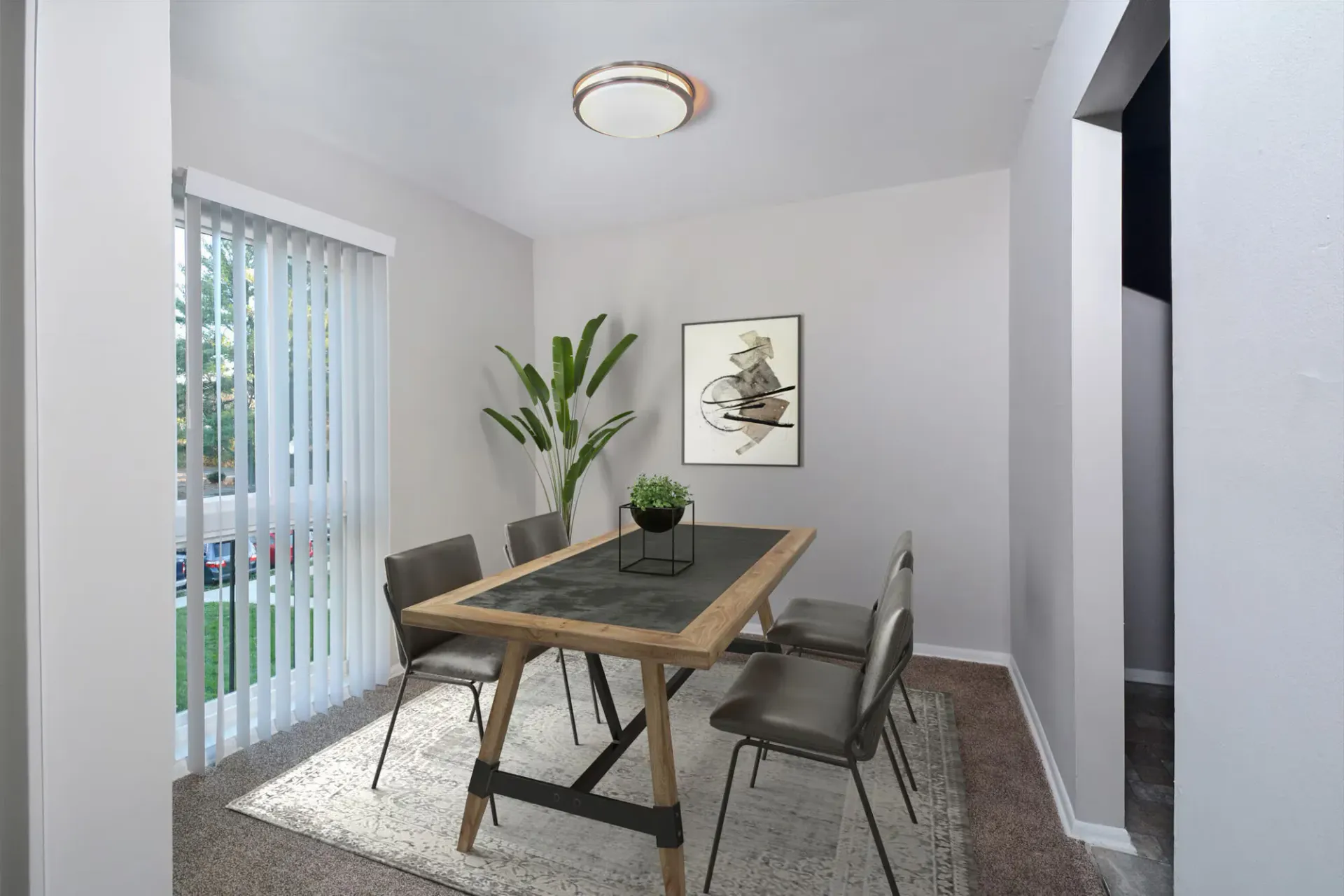 Dining room in a modern apartment with a wood table, four chairs, plant, and vertical blinds at Metro Pointe in Baltimore, MD.