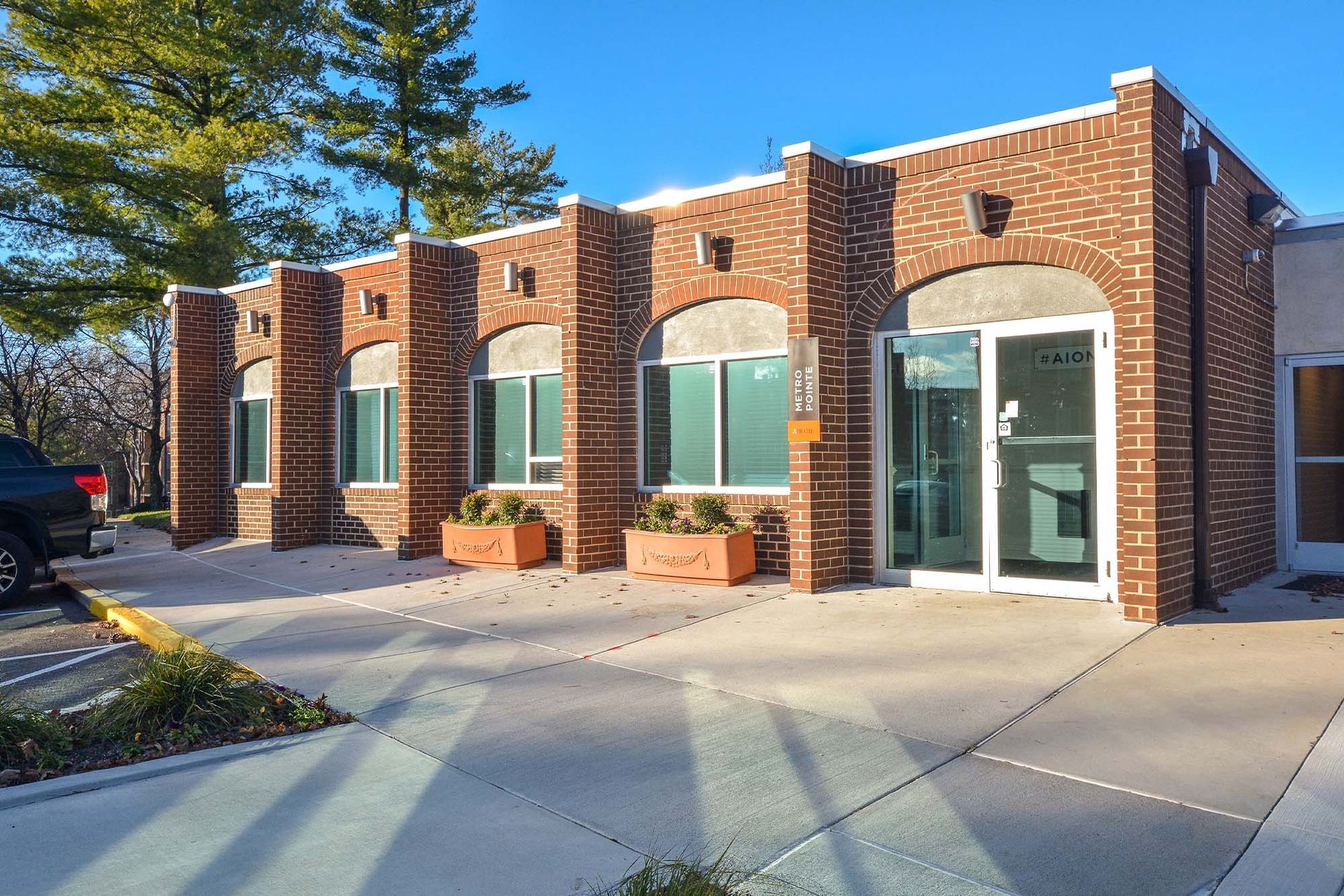 Exterior brick building entrance with arched windows, planters, and a glass door at Metro Pointe in Baltimore, MD.