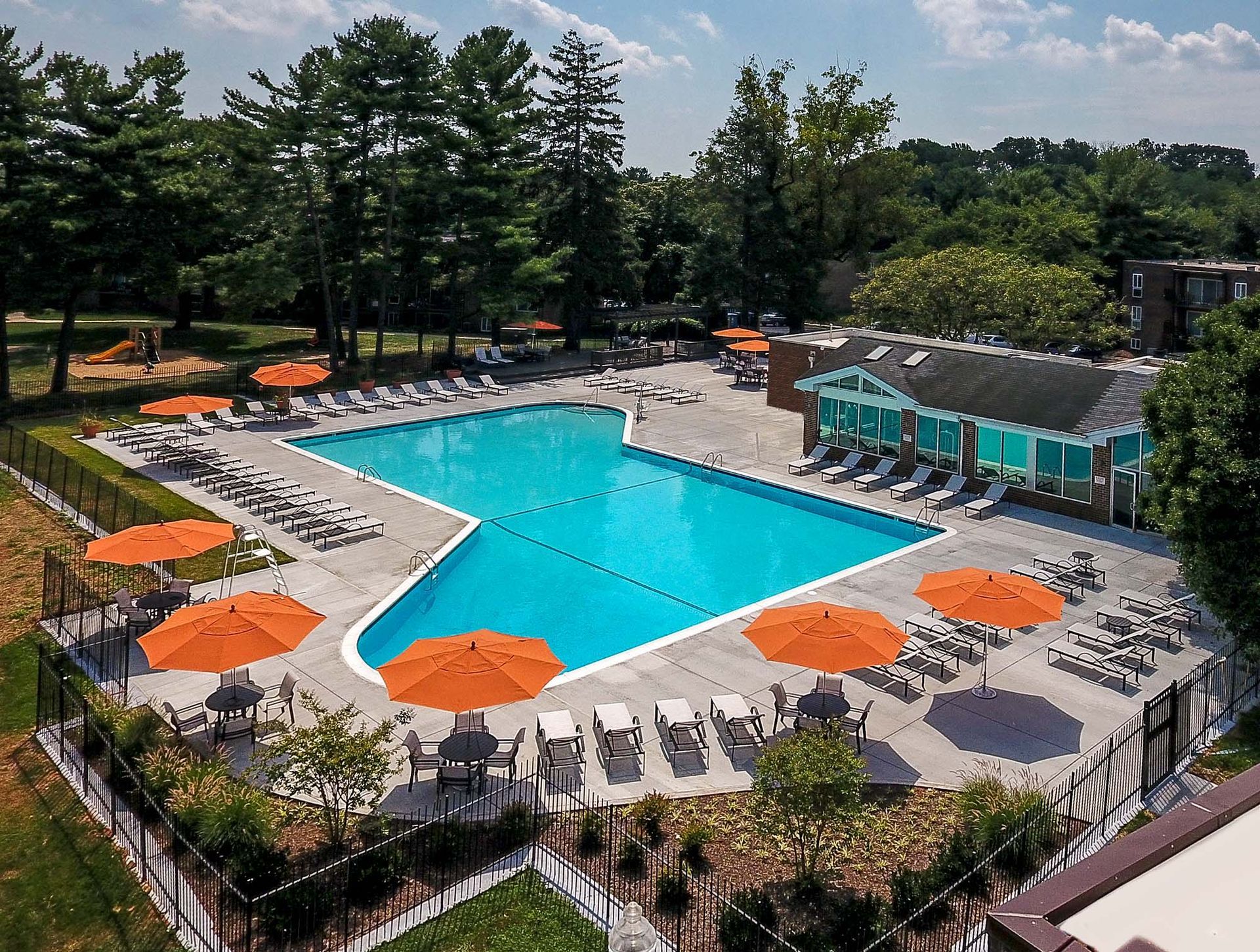 Aerial view of a large outdoor pool surrounded by lounge chairs and orange umbrellas at an apartment complex at Metro Pointe in Baltimore, MD.