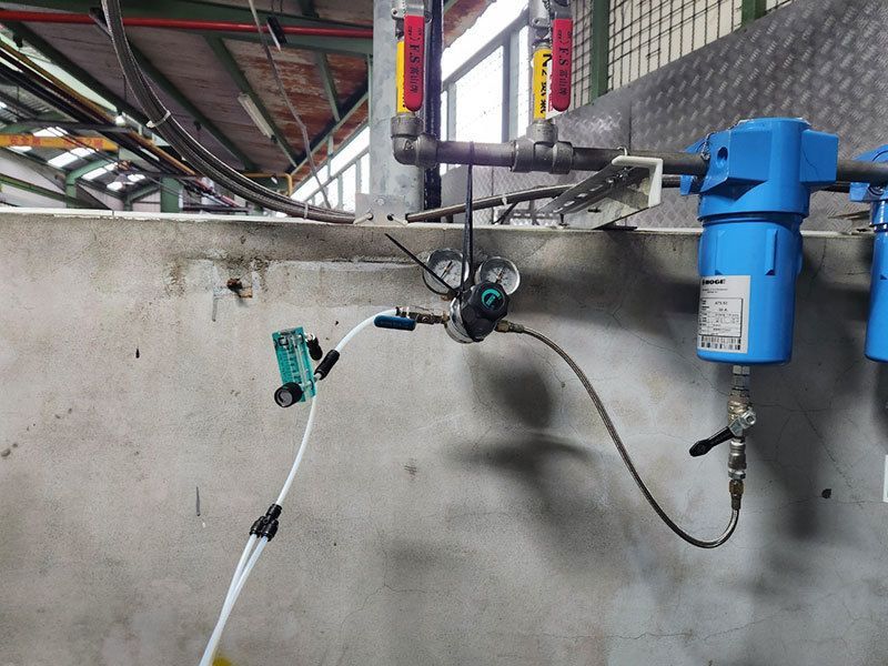 A hose is connected to a blue device on a wall.