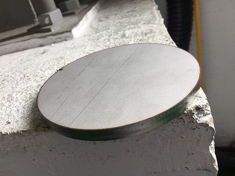 A round piece of metal is sitting on a concrete surface