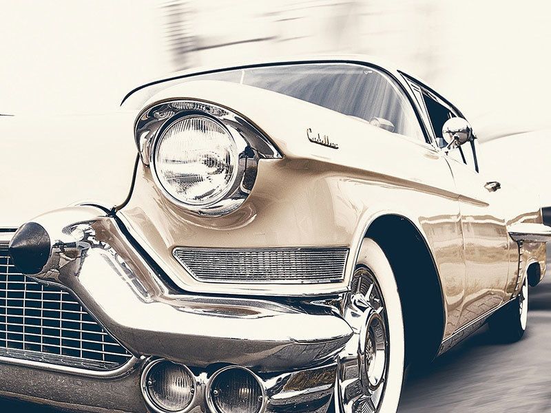 A close up of an old car driving down a street.