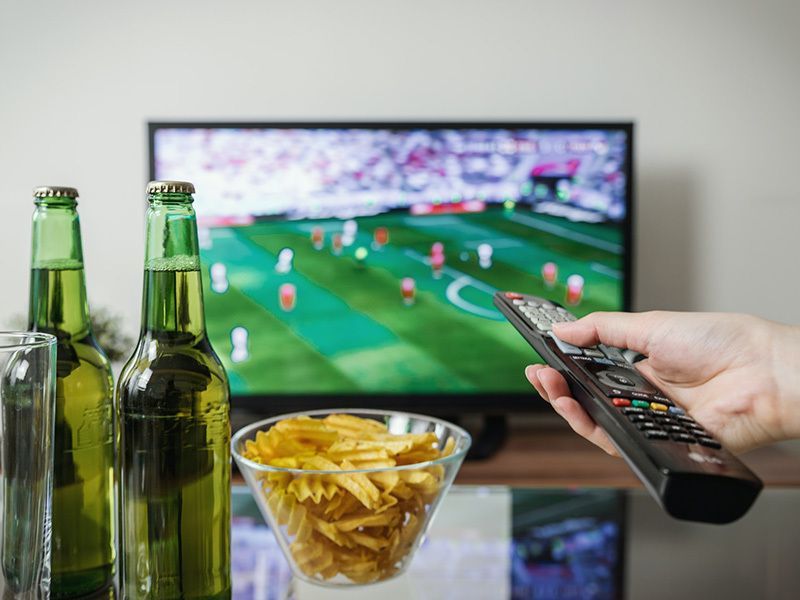 A person is holding a remote control in front of a television.