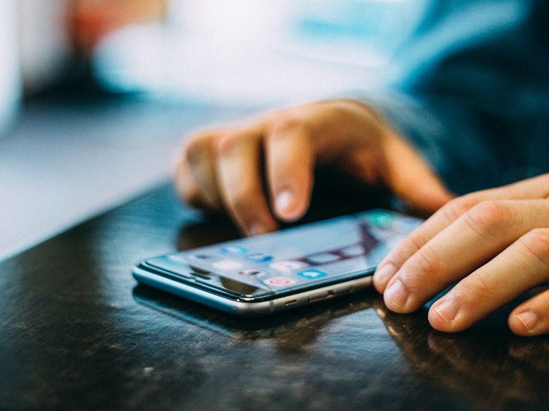A person is using a cell phone on a table.