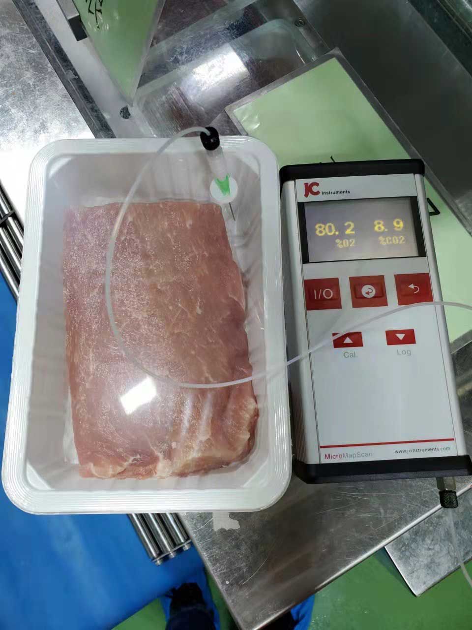A piece of meat in a plastic container next to a digital device