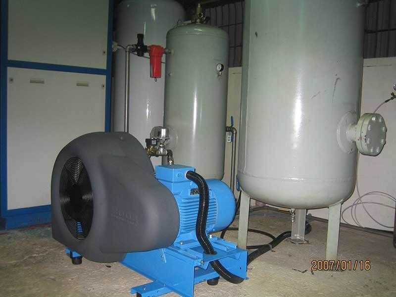 A blue air compressor is sitting next to a tank in a room.