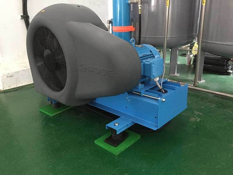 A large blue fan is sitting on a green floor in a room.