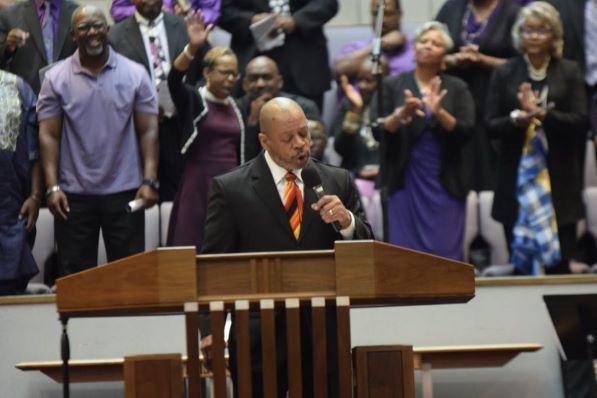 A man stands at a podium with a microphone in front of a crowd of people