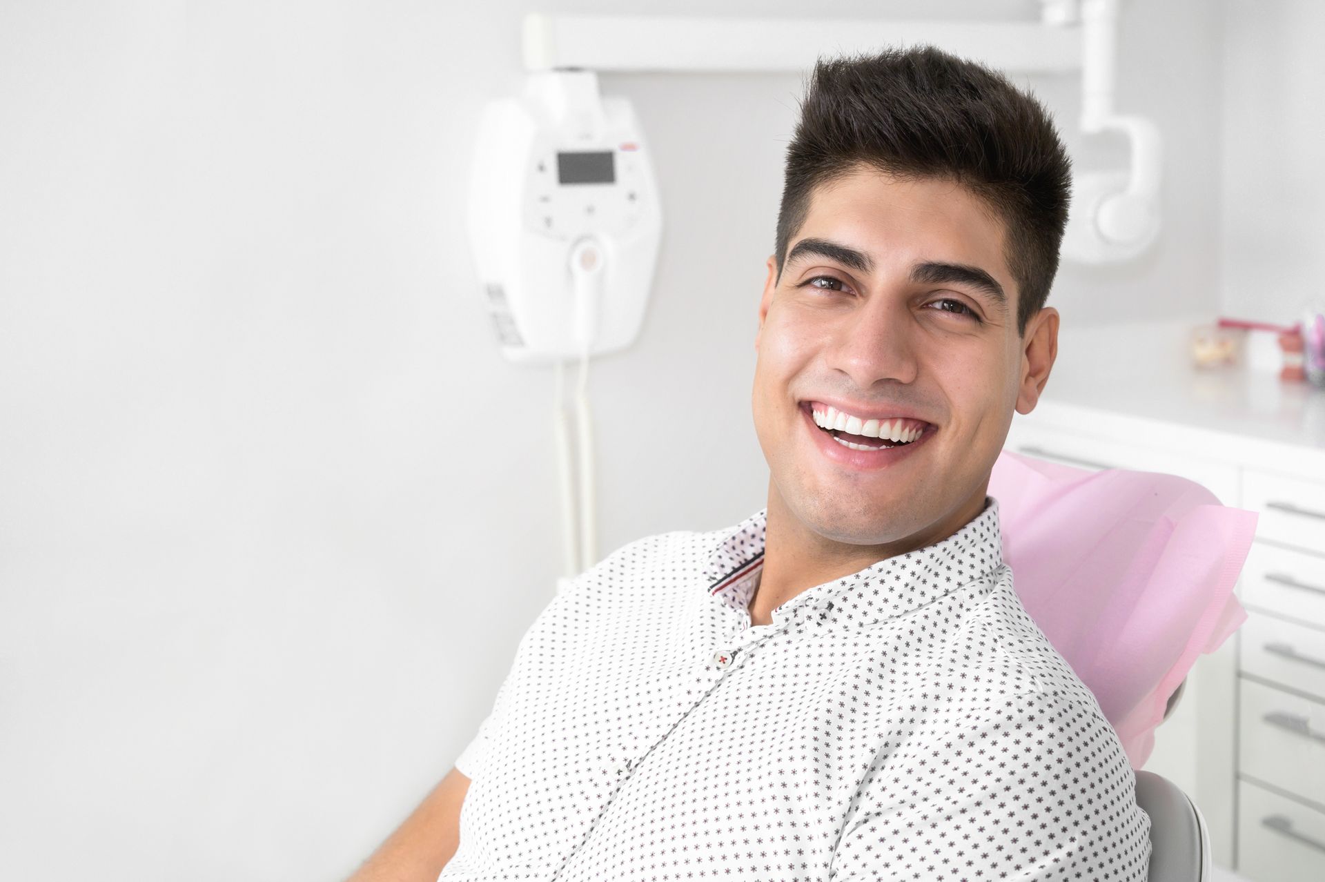 A young man is smiling while sitting in a dental chair.