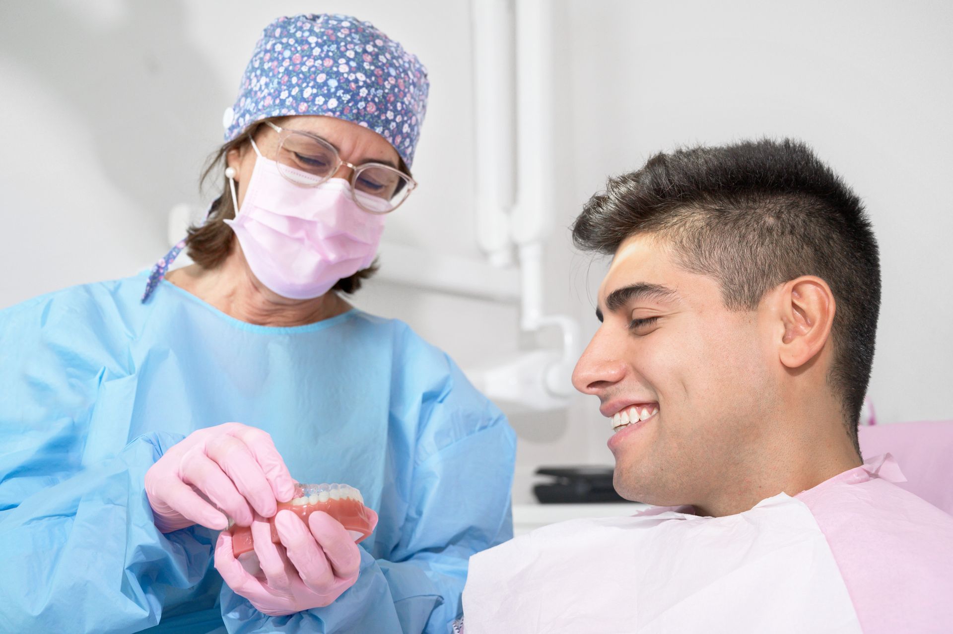 A dentist is examining a man 's teeth in a dental office.