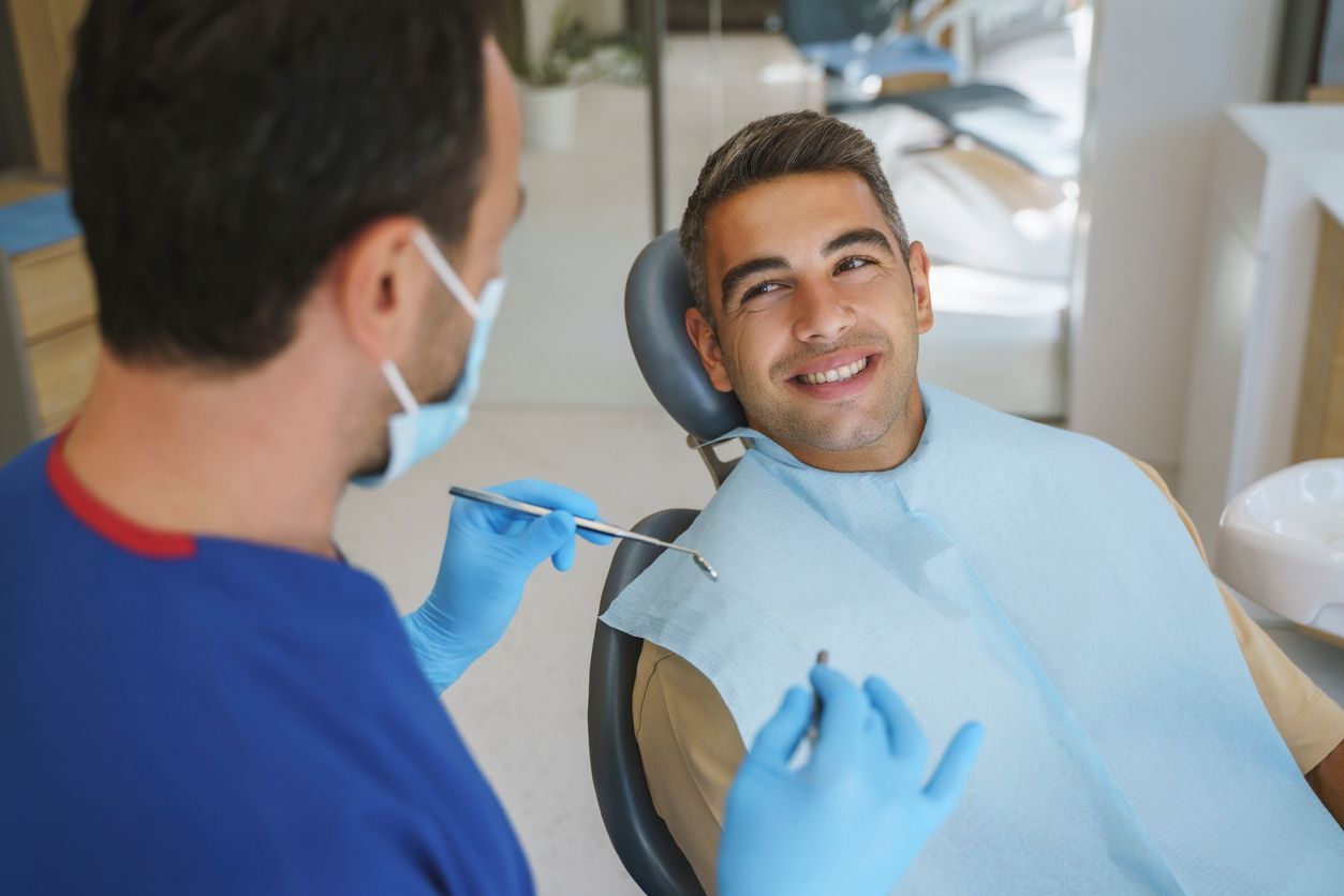 A dentist and a patient are looking at a tablet together.