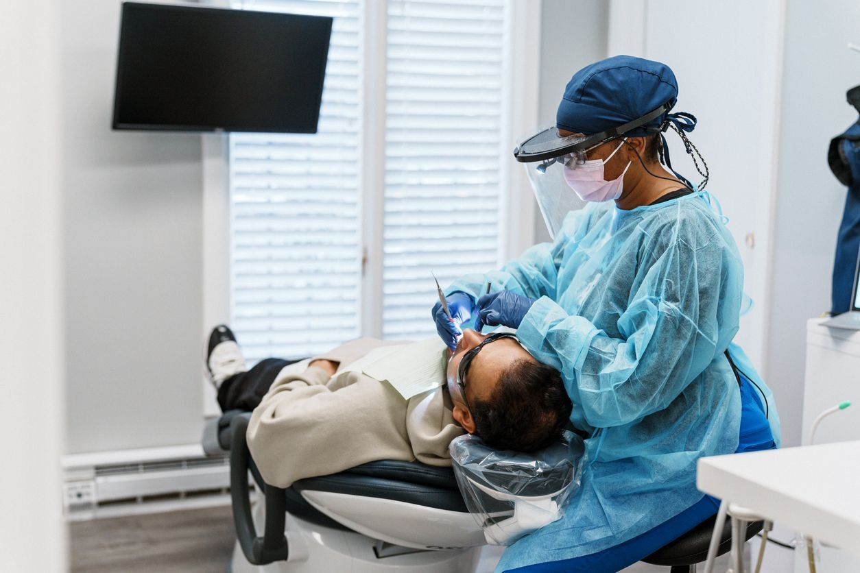 A dentist is examining a patient 's teeth in a dental office.