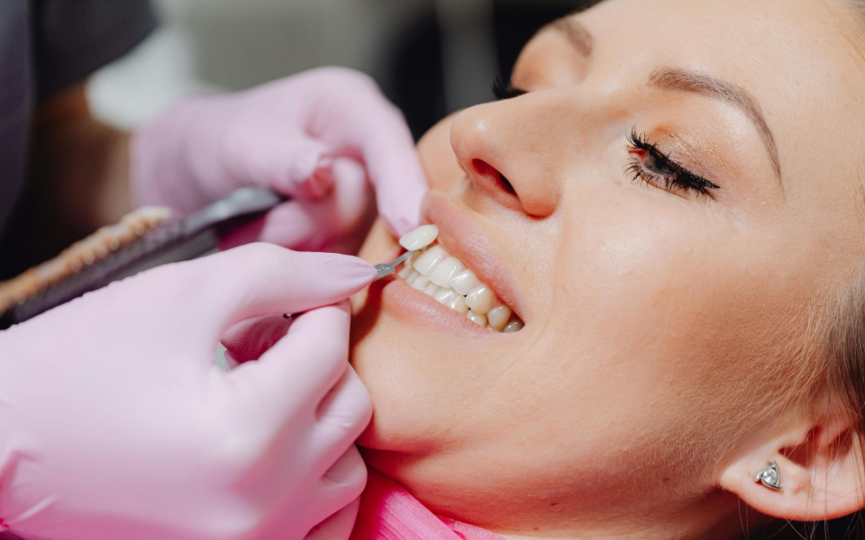 Dentist examining patient's teeth with gloved hands.