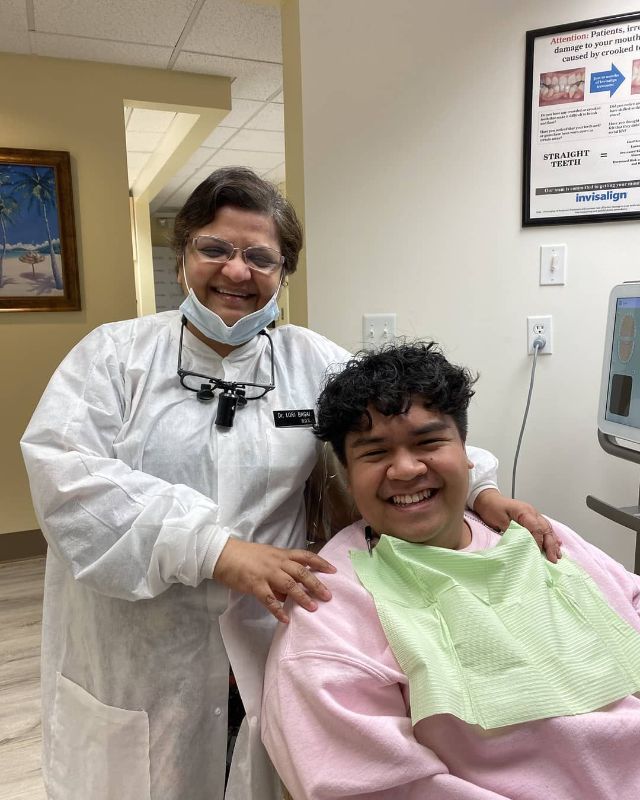 A dentist is posing for a picture with a patient in a dental chair.