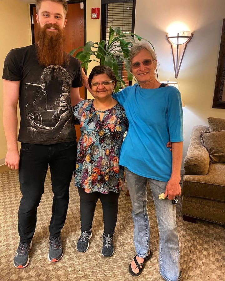 A man with a beard is posing for a picture with two women