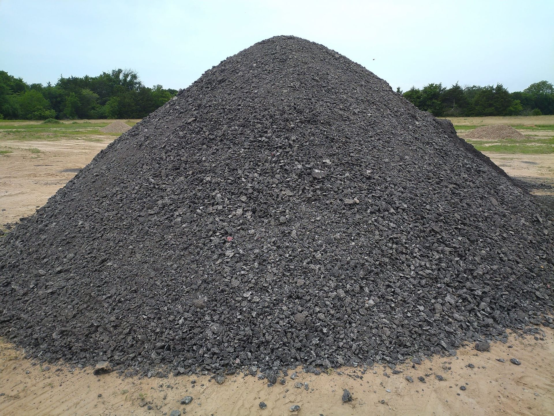 A pile of dirt is sitting on the side of a road next to a house.