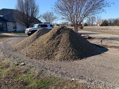 A pile of dirt is sitting on the side of a road next to a house.