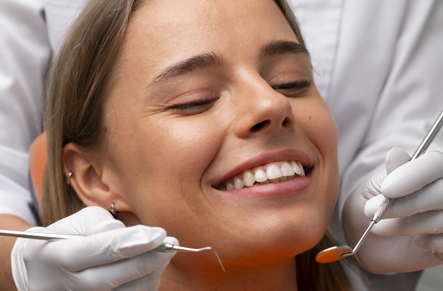 A woman is smiling while having her teeth examined by a dentist.