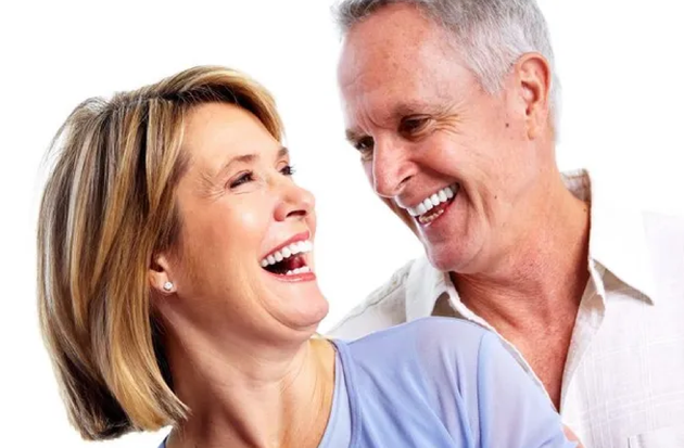 A man and a woman are laughing together and looking at each other.