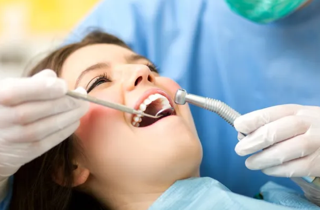 A woman is getting her teeth examined by a dentist.