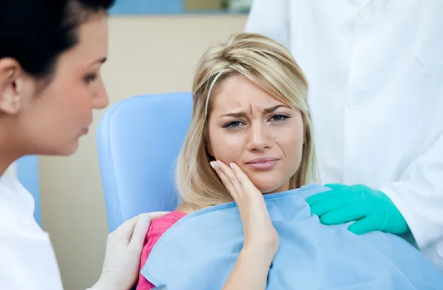 A woman is sitting in a dental chair with a toothache.