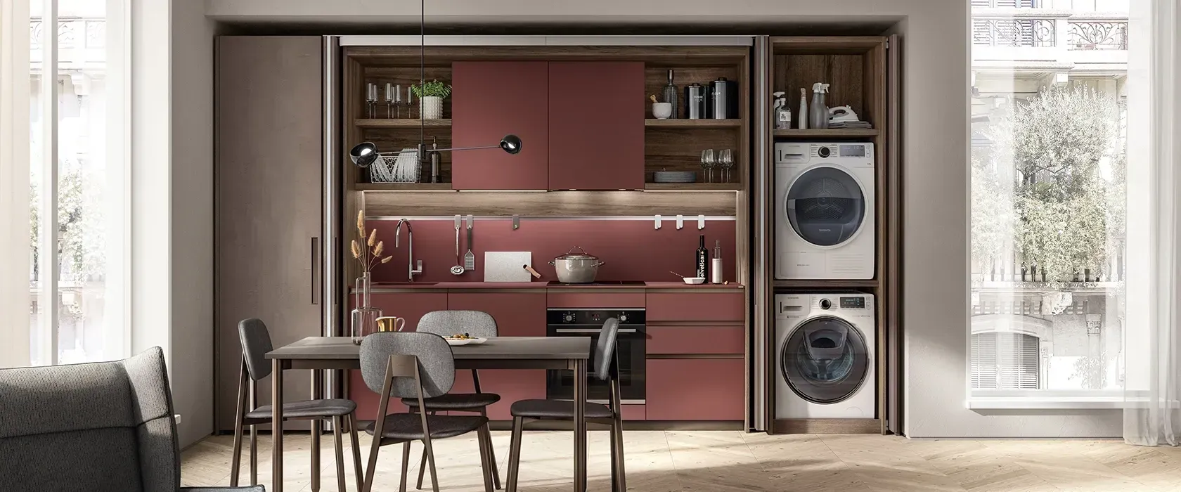 Angolo cucina-sala da pranzo a pianta aperta con mobili rossi, tavolo e sedie e lavatrice e asciugatrice integrate sulla destra.