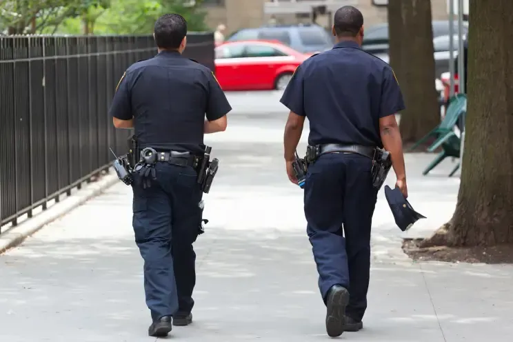 Two police officers are walking down the street