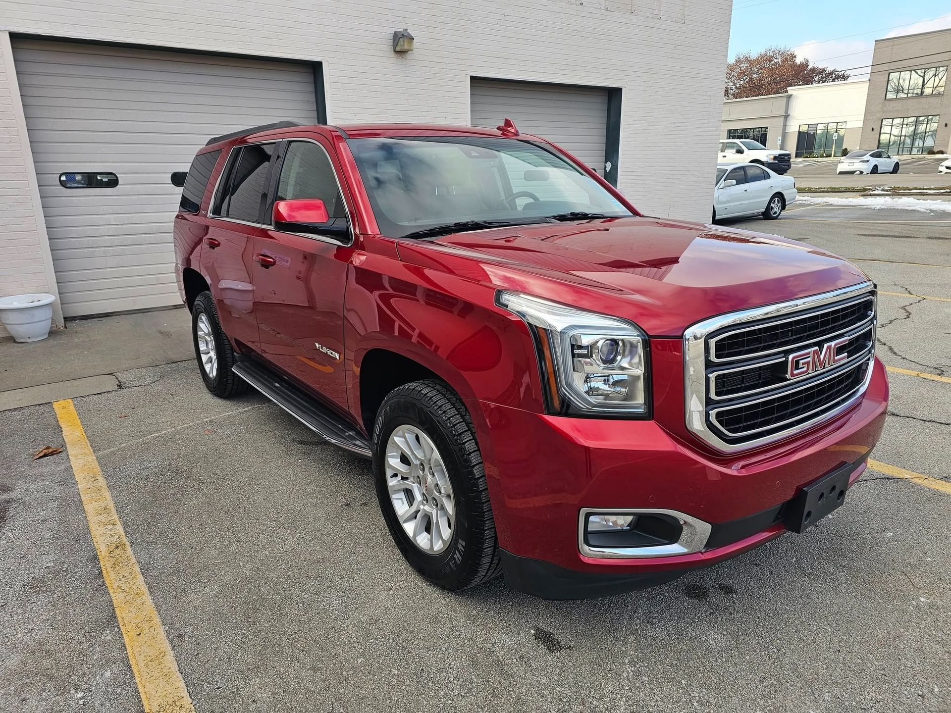 A worker applies protective film to the glossy grey exterior of a modern car in a workshop.