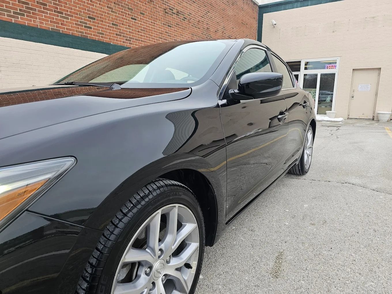 White BMW sedan side view, focusing on the rear wheel with a multi-spoke alloy rim and tan interior visible through the door.