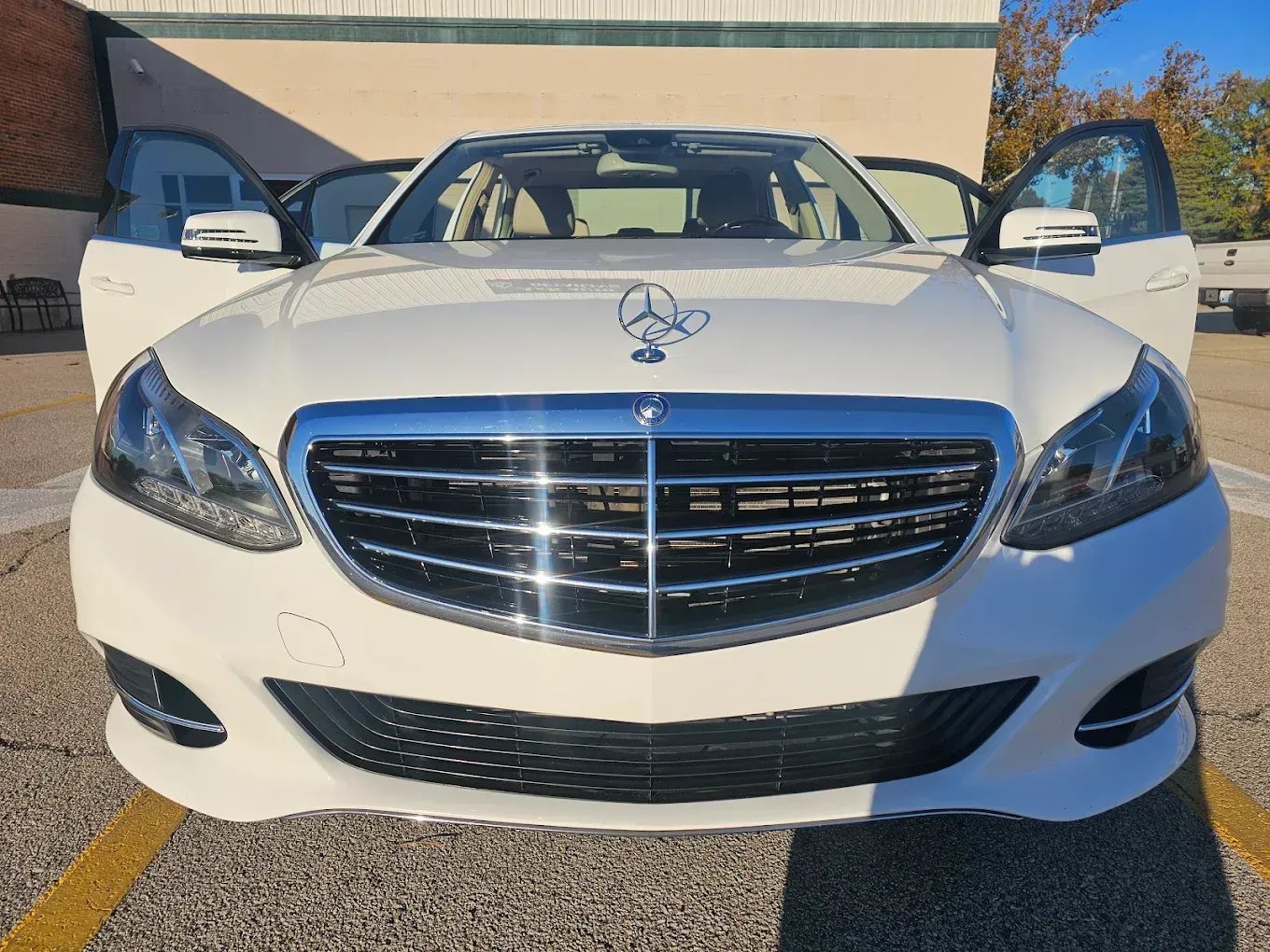 A cream-colored vintage Cadillac sedan parked in a cluttered auto repair garage.