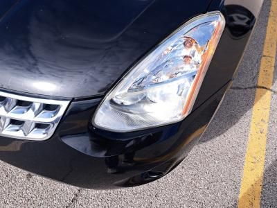 The front headlight, hood, and chrome grille of a black car parked next to a yellow parking space line.
