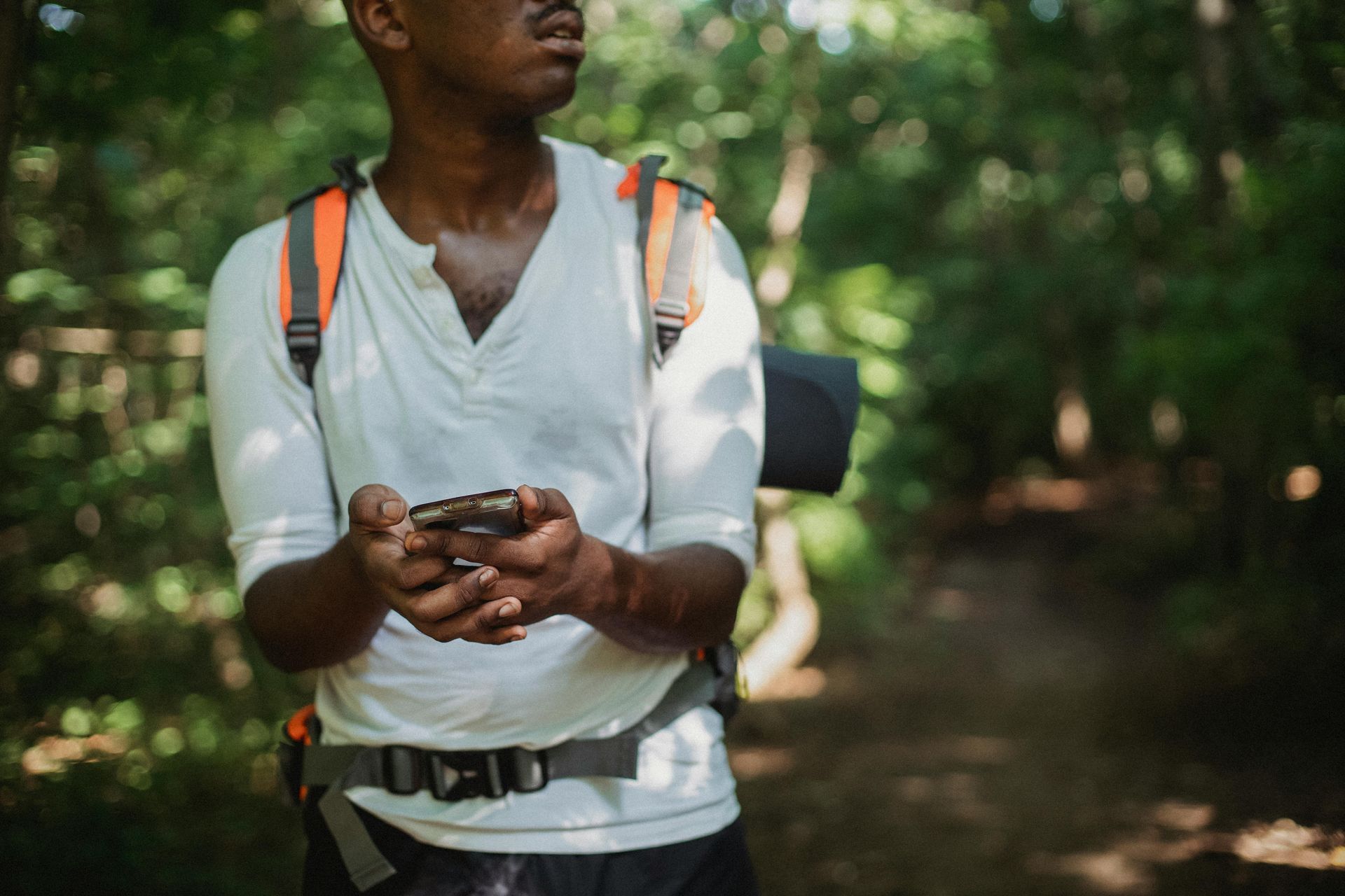 A man with a backpack is taking a picture in the woods.