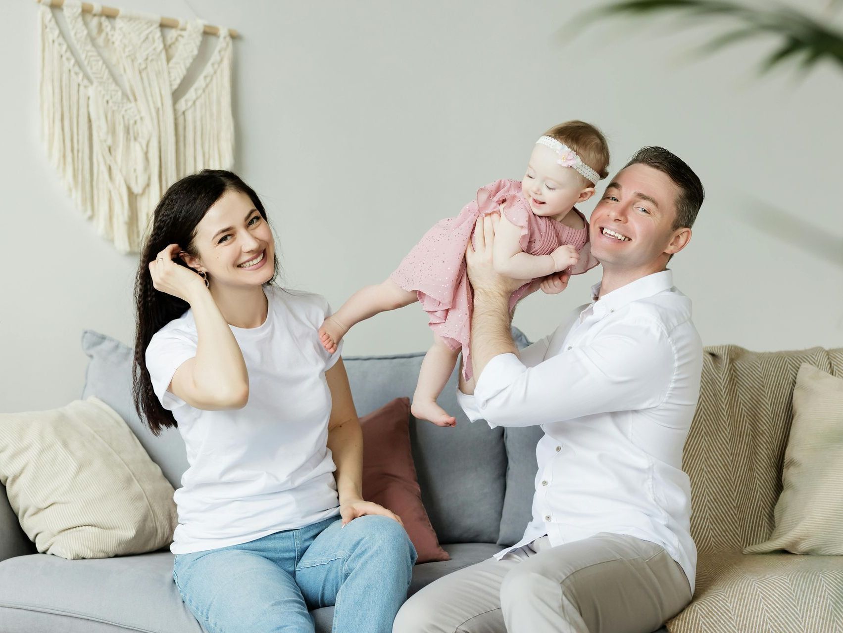A man and woman are sitting on a couch holding a baby.