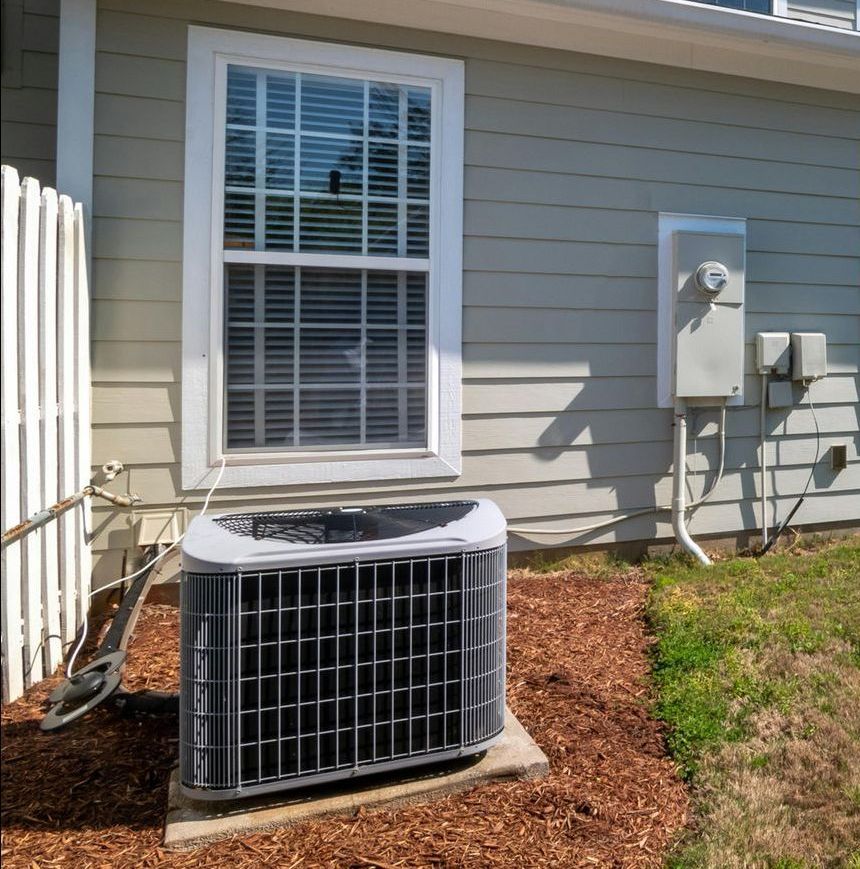 An air conditioner sits outside of a house next to a window