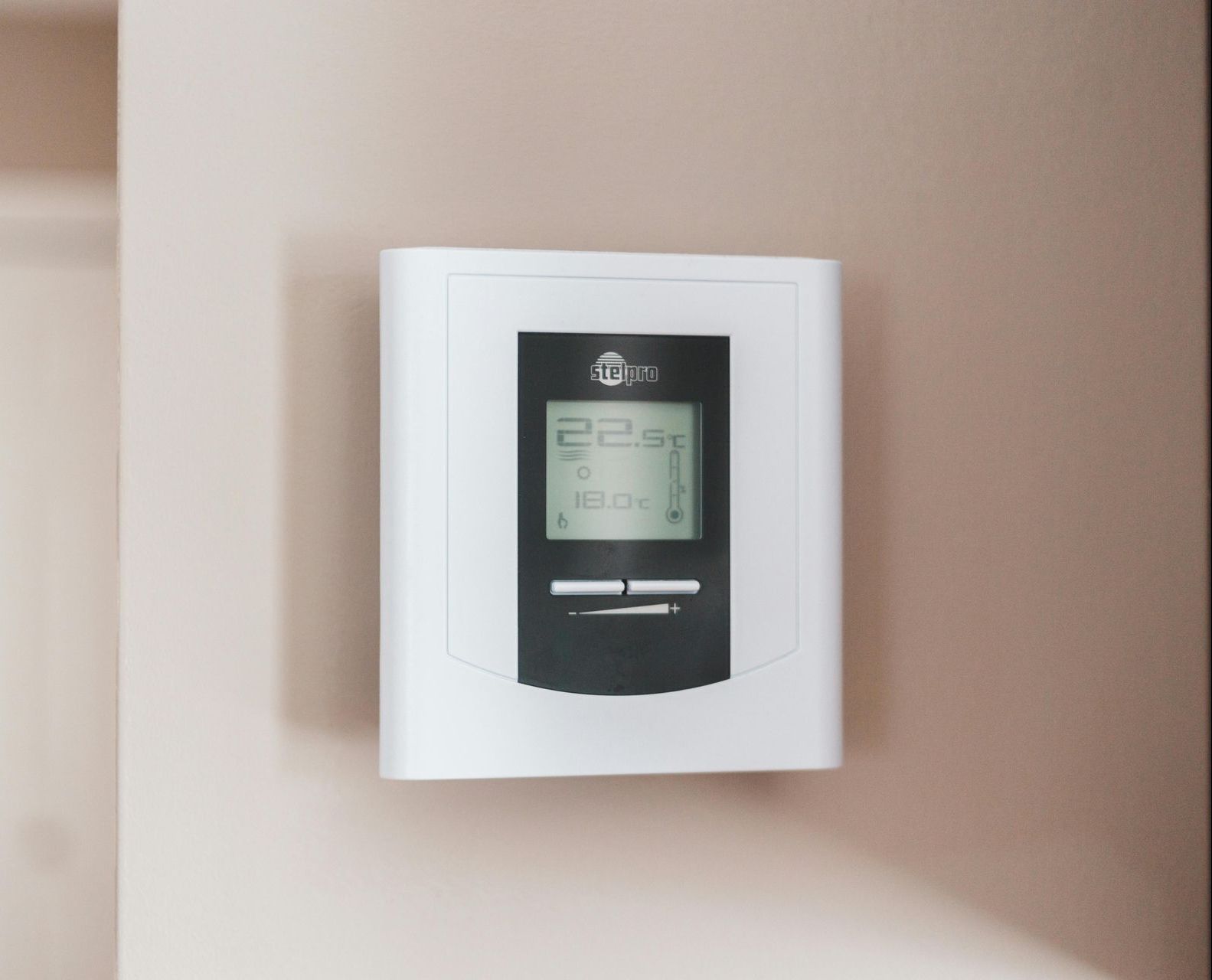 A thermostat on a wall shows the temperature is 22 degrees