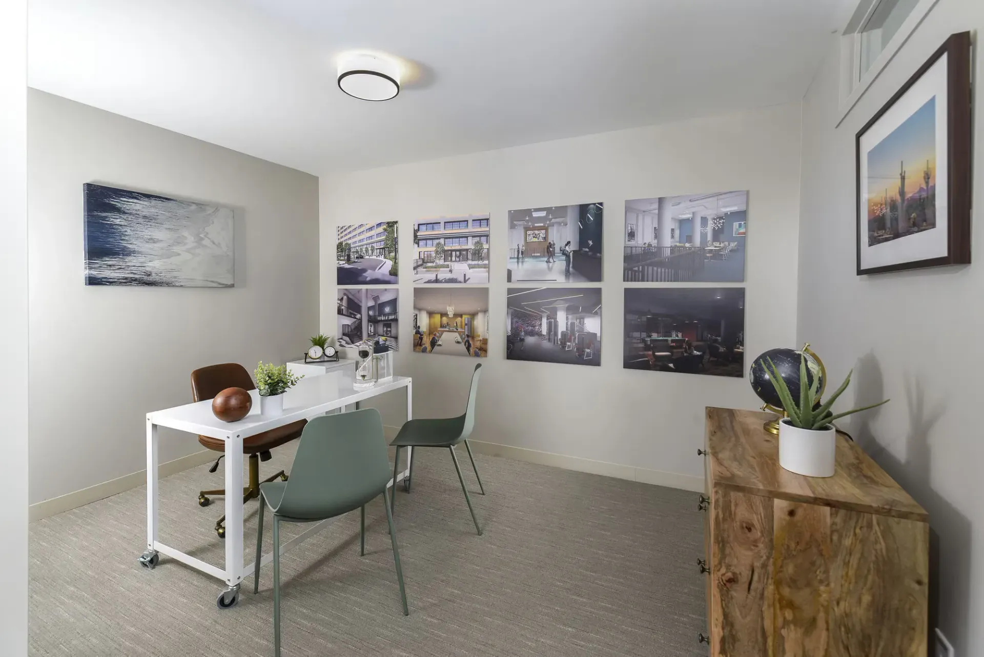 Leasing office in a modern community room with a white desk, two chairs, and wall photo collage at Terminal 21, a premier apartment community in Downtown Pittsburgh, Pennsylvania.