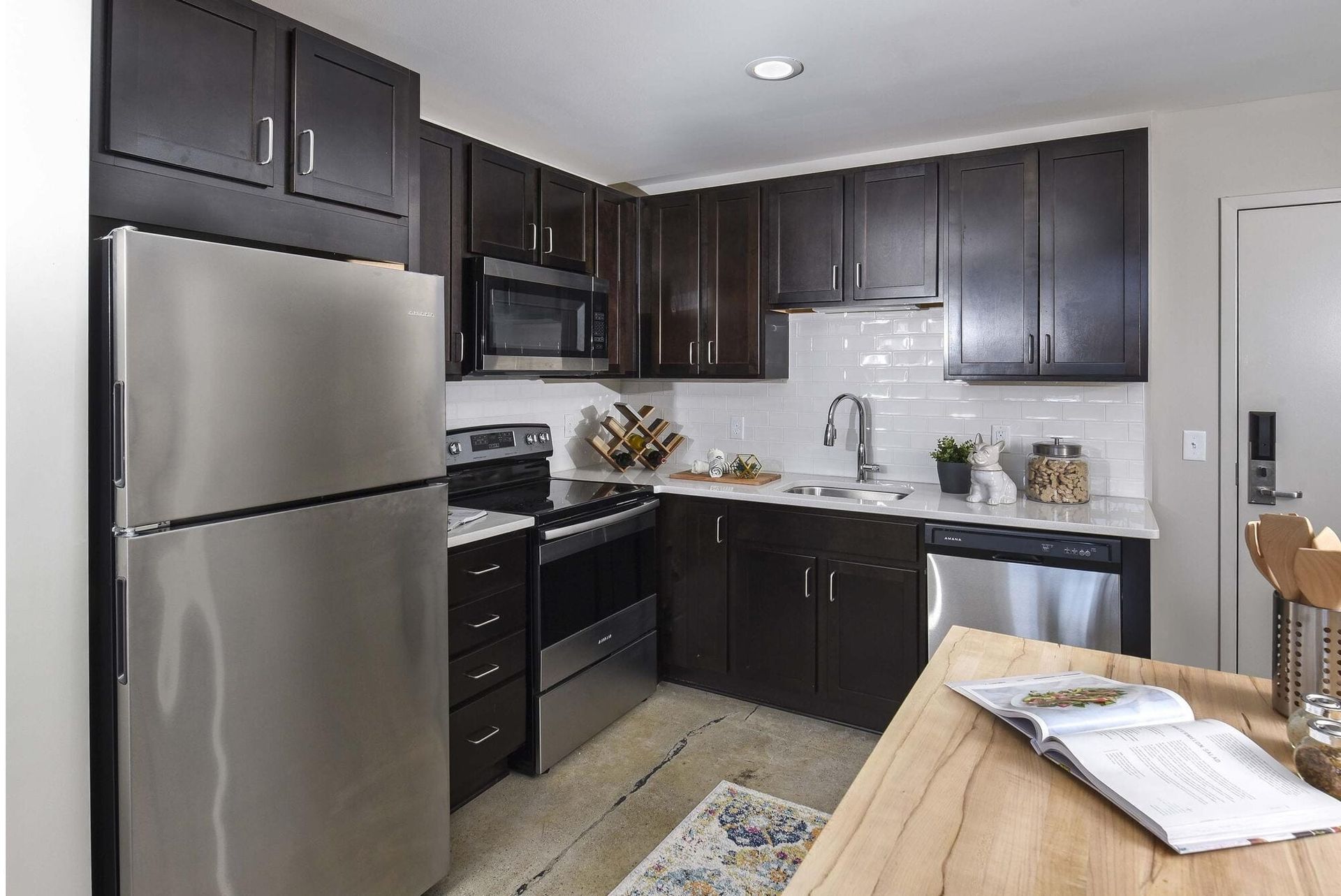 Modern kitchen with dark cabinets, stainless steel fridge, and white subway tile backsplash at Terminal 21, a premier apartment community in Downtown Pittsburgh, Pennsylvania.