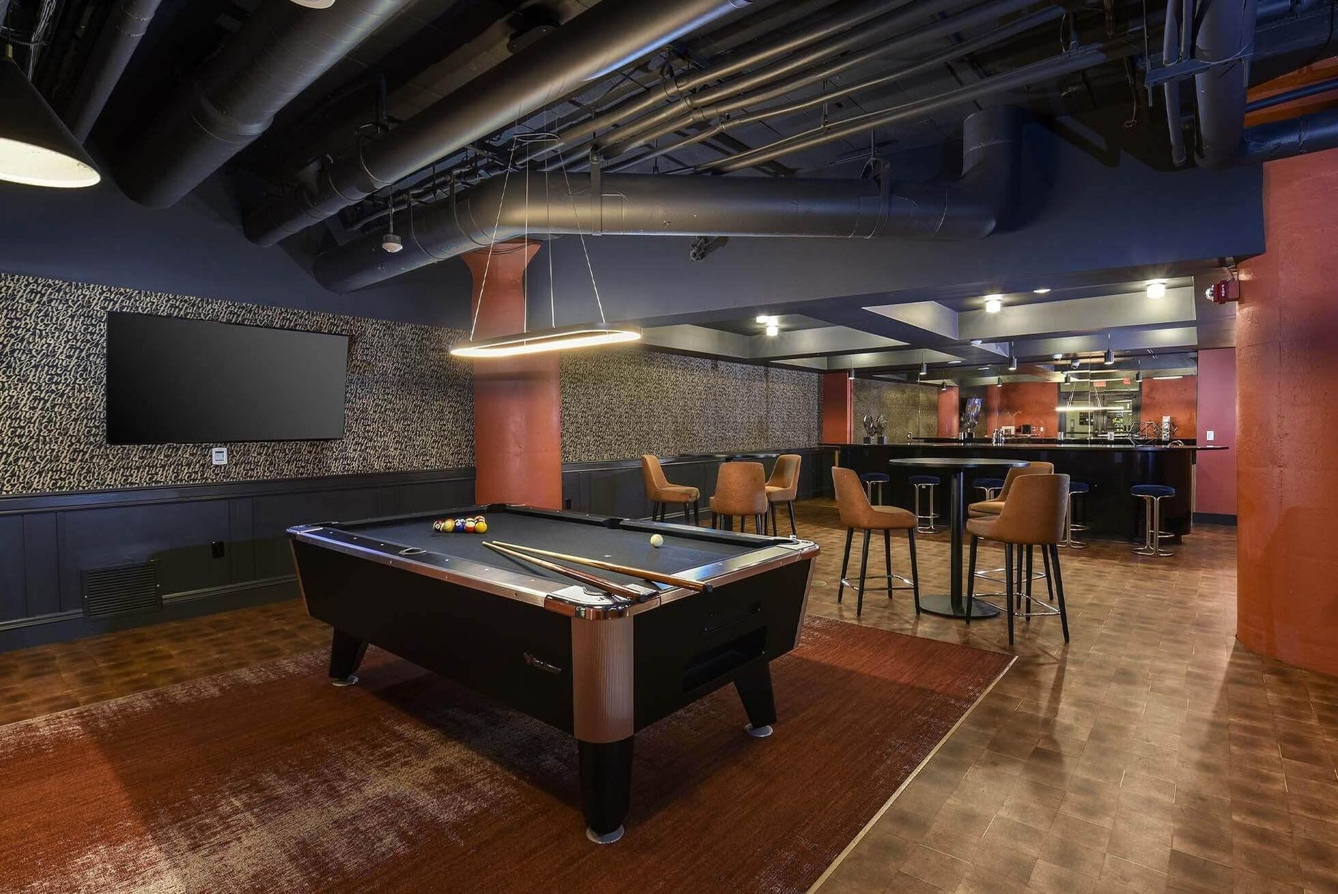 Indoor community recreation room with a pool table, lounge seating, and a bar at Terminal 21, a premier apartment community in Downtown Pittsburgh, Pennsylvania.