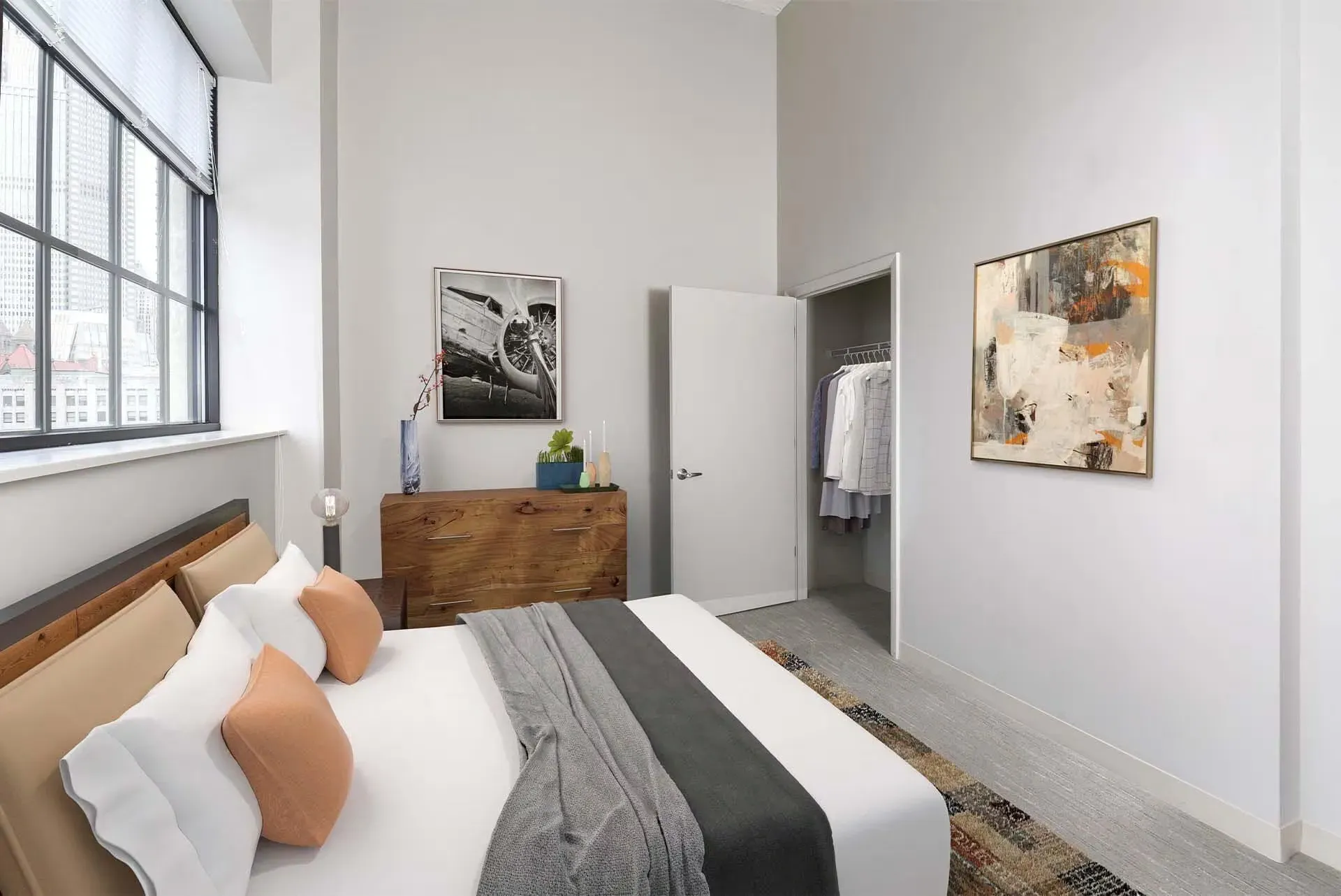 Bedroom in an apartment with a bed, dresser, open closet, and abstract wall art at Terminal 21, a premier apartment community in Downtown Pittsburgh, Pennsylvania.