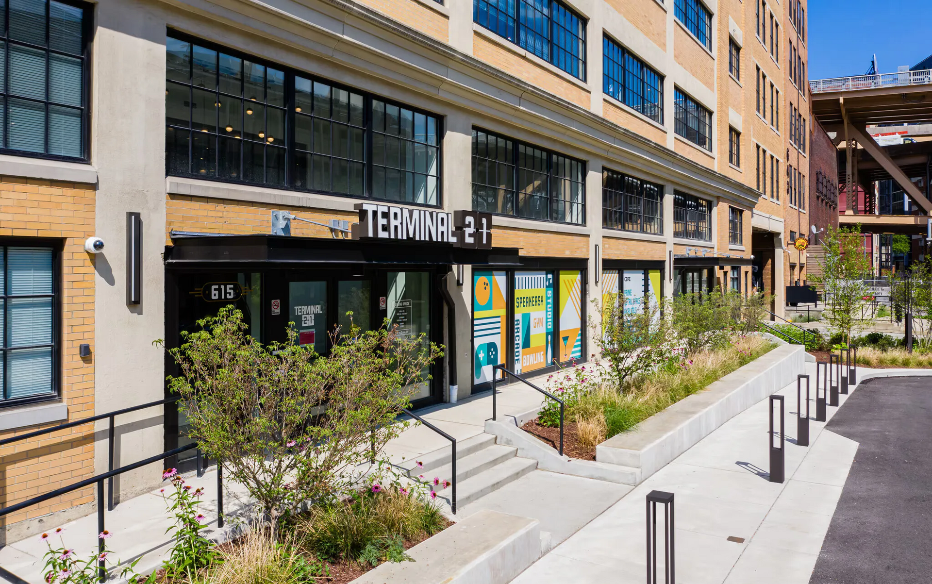 Exterior view of a brick apartment building with a storefront labeled Terminal 21 and a landscaped walkway.