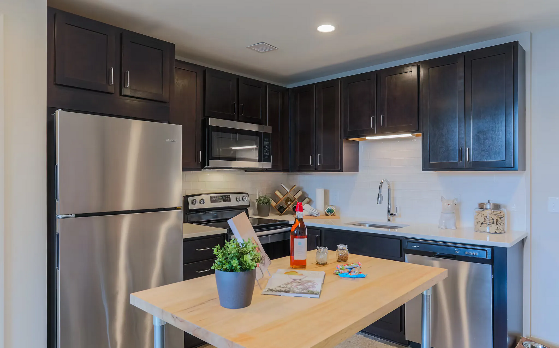 Modern kitchen in an apartment with dark wood cabinets, stainless steel appliances, and a wood island at Terminal 21, a premier apartment community in Downtown Pittsburgh, Pennsylvania.