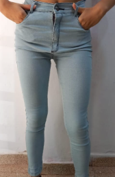 Vaqueros pitillo de mezclilla azul con rodillas rotas y adornos plateados en los tobillos.