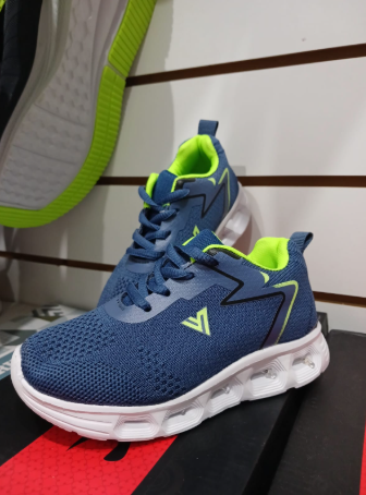 Zapatillas deportivas azules y verdes con suelas blancas en exposición.