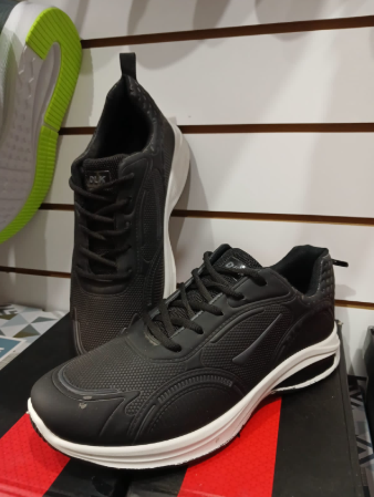 Zapatillas deportivas negras con suelas blancas en un estante de exhibición.